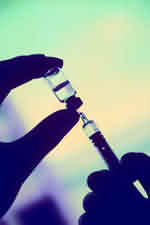 Photo of a syringe being filled with the vaccine from its bottle